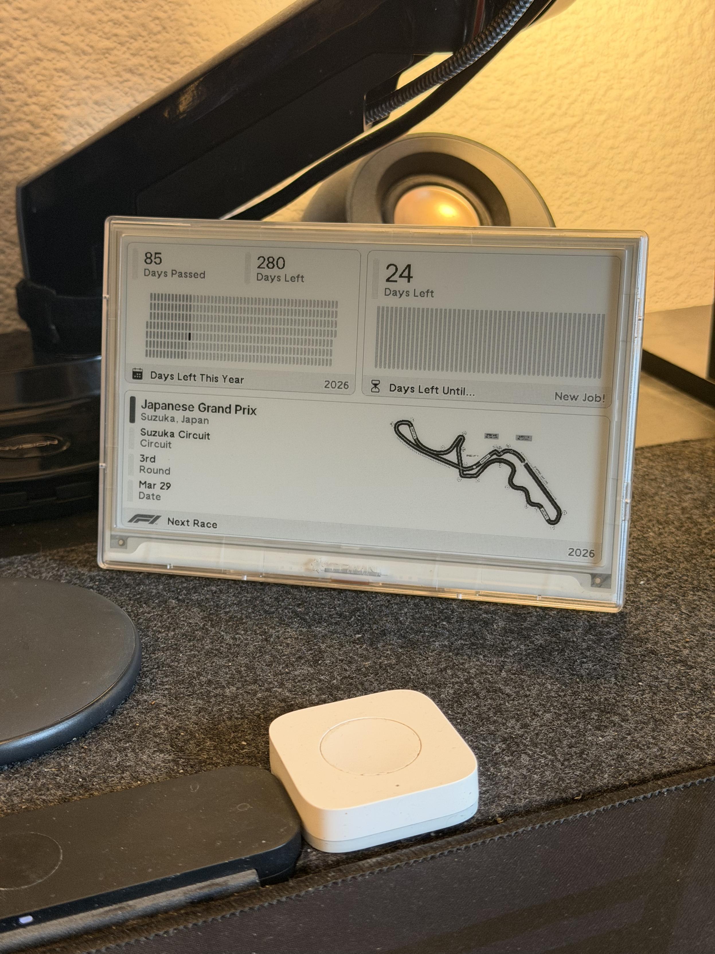 An e-ink display sat on a desk shows days left in the year, days left until new job, and a map of the Japanese F1 circuit at Suzuka.